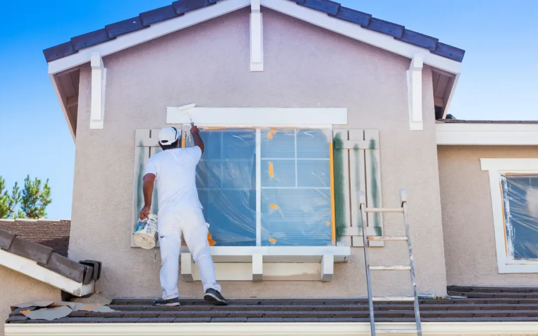 Artisan peintre appliquant une peinture extérieure sur la façade d'une maison dans le Pays de Gex